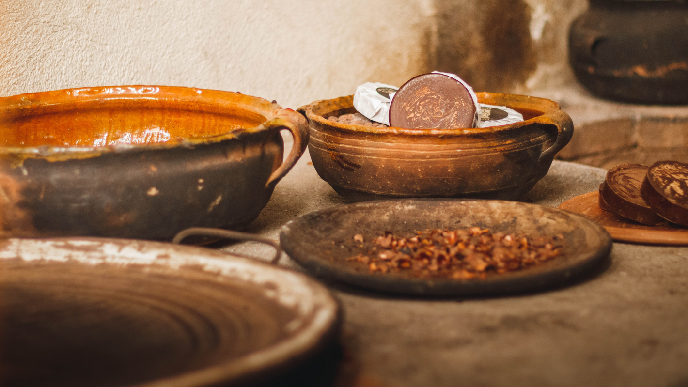 Zeremonieller Kakao in traditionellen Tongefäßen auf einem Tisch. Außerdem eine Schale mit Kakao-Tee aus den Hülsen der Kakaobohnen.