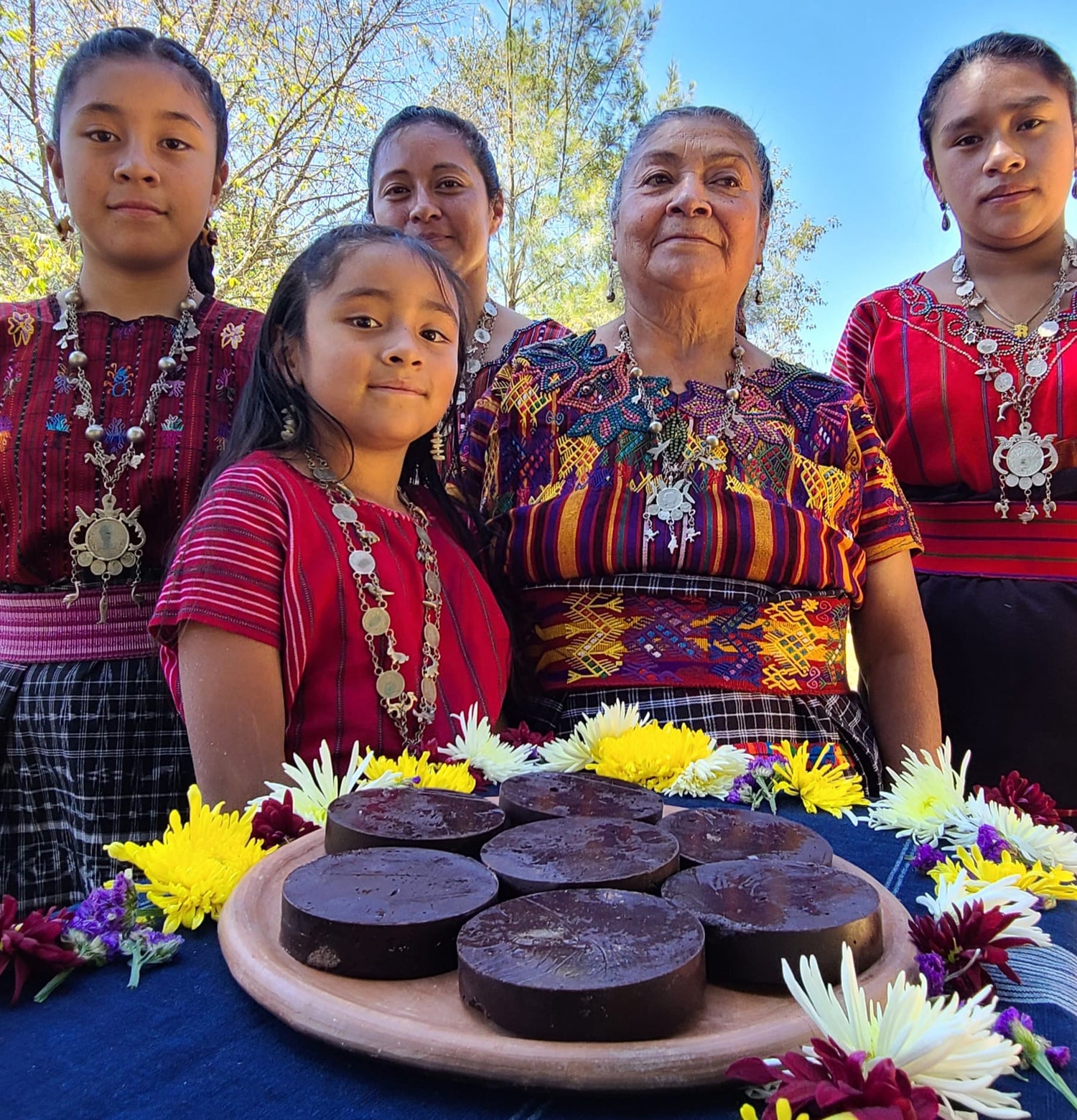 Maya Frauen aus Guatemala verschiedener Generationen stehen hinter einem Tisch mit Kakaoblöcken 