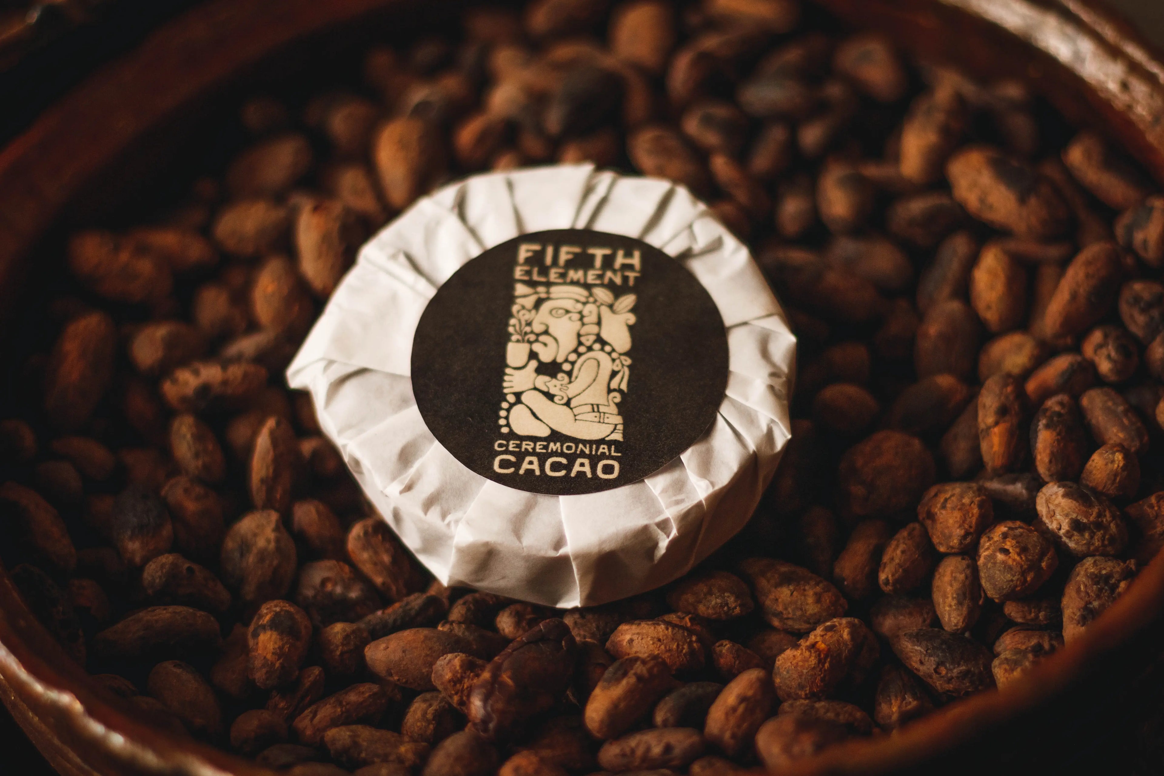 Ceremonial cacao from Fifth Element placed on roasted cacaobeans in a clay bowl