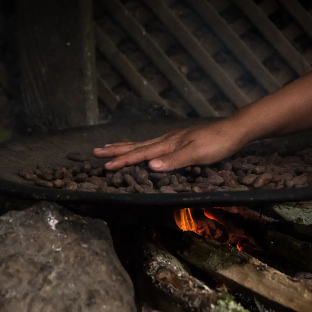 Cacao beans are being roasted gtraditionally by hand over an open fire